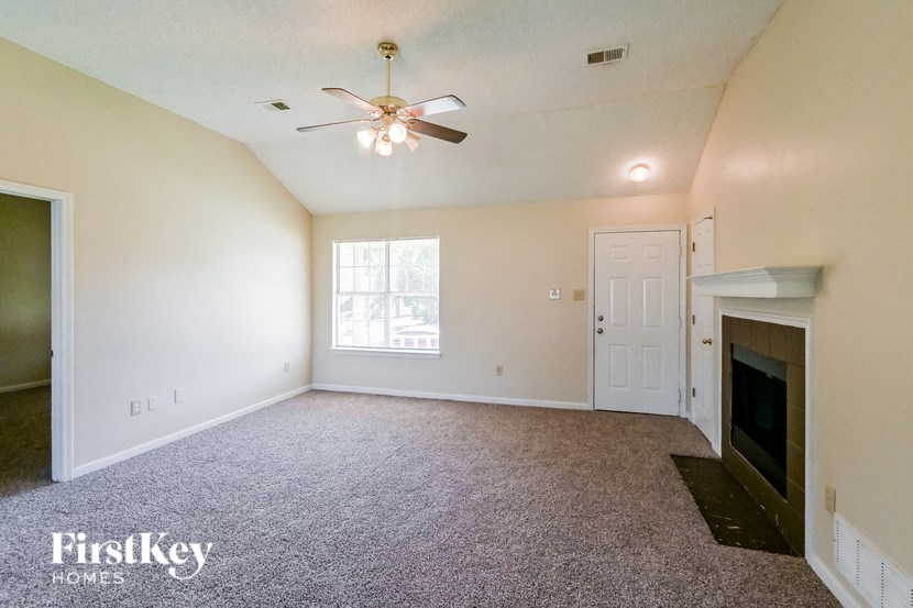 an empty living room with a fireplace and a ceiling fan