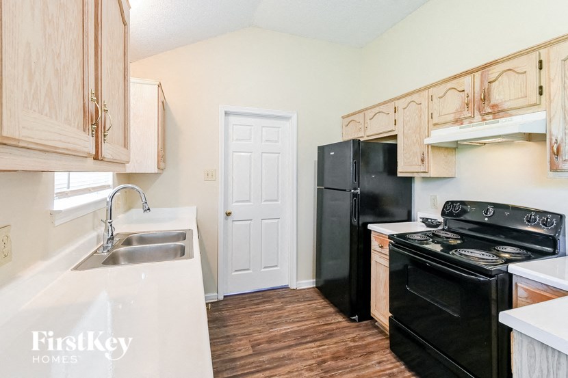 a kitchen with a black stove and refrigerator and a sink