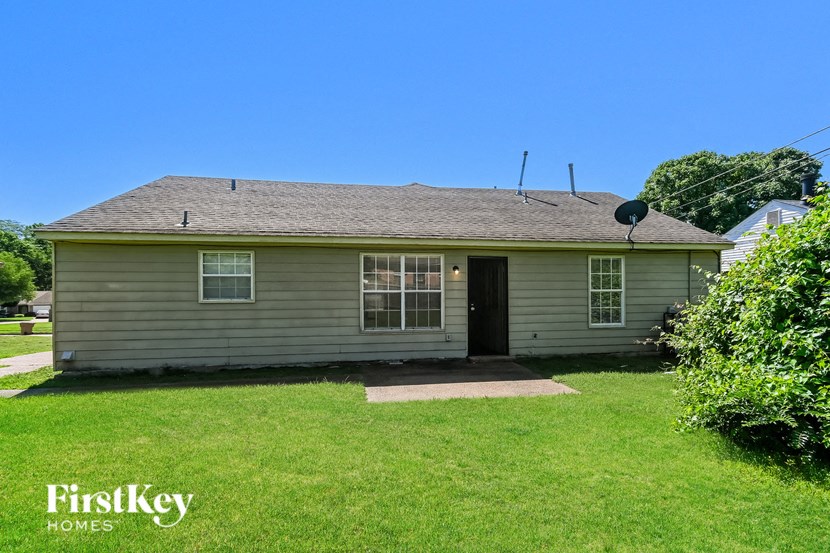 the front of a house with a green lawn and a blue sky