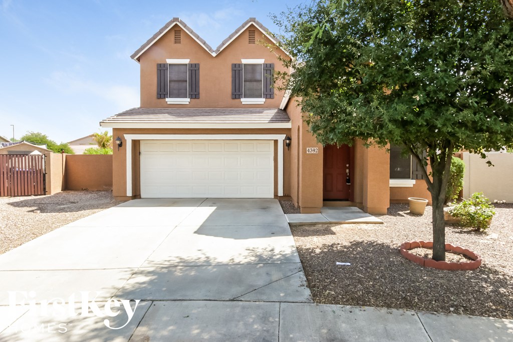 a house with a driveway and a tree in front of it