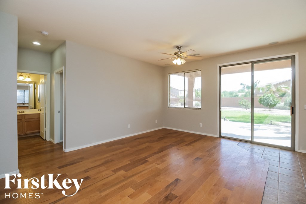 an empty living room with wood floors and a ceiling fan