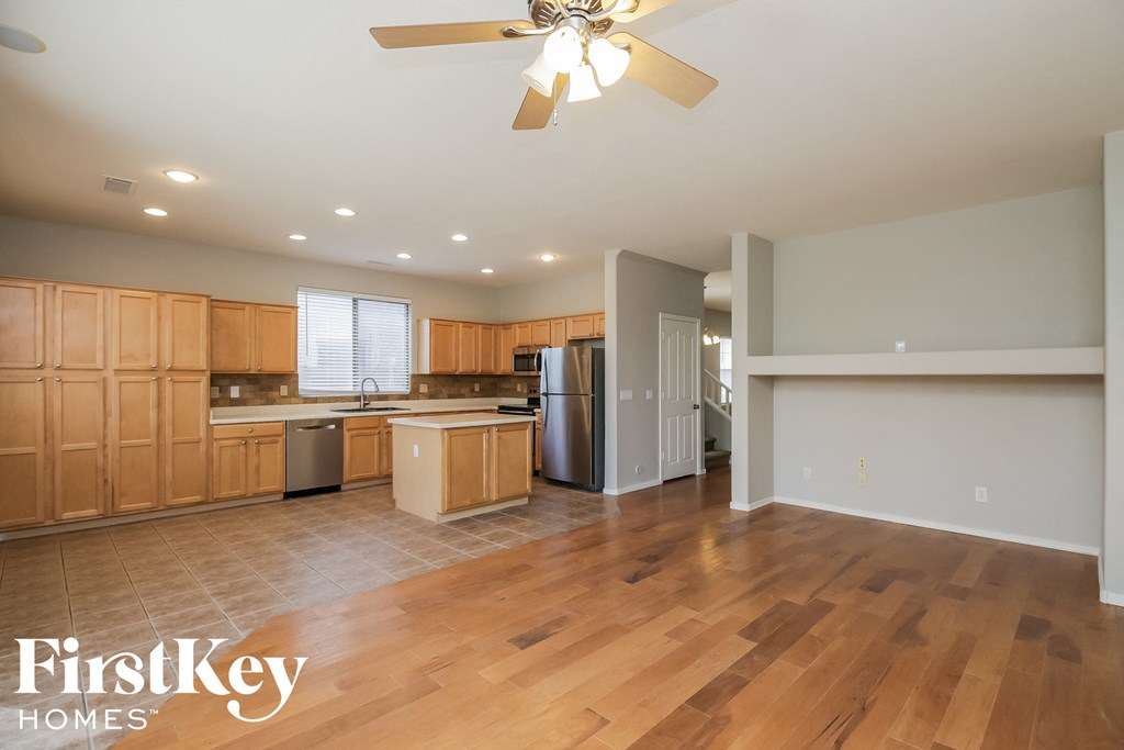 an open kitchen and living room with wood flooring and a ceiling fan