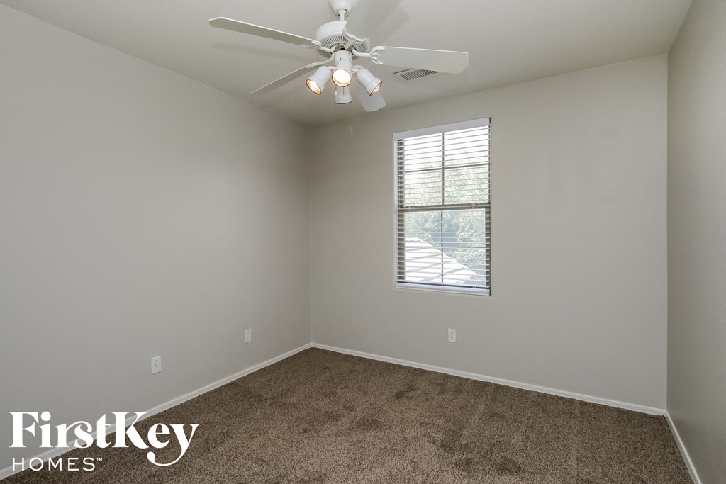 a empty room with a ceiling fan and a window