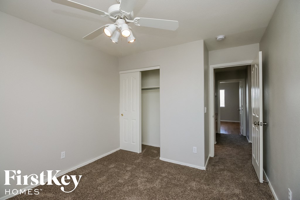 a bedroom with a ceiling fan and a hallway with a closet