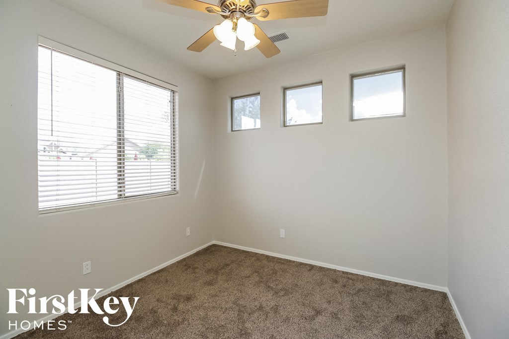 a empty room with a ceiling fan and three windows