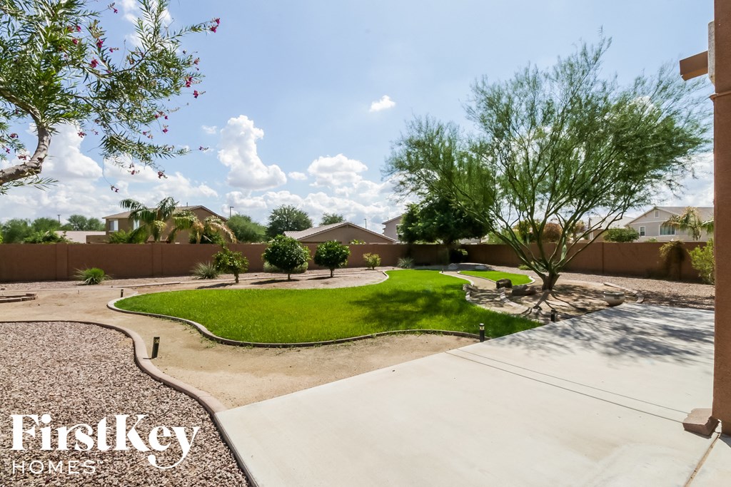 a yard with grass and trees and a sidewalk