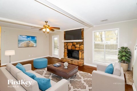 A living room with a fireplace and a painting of a beach scene on the wall.