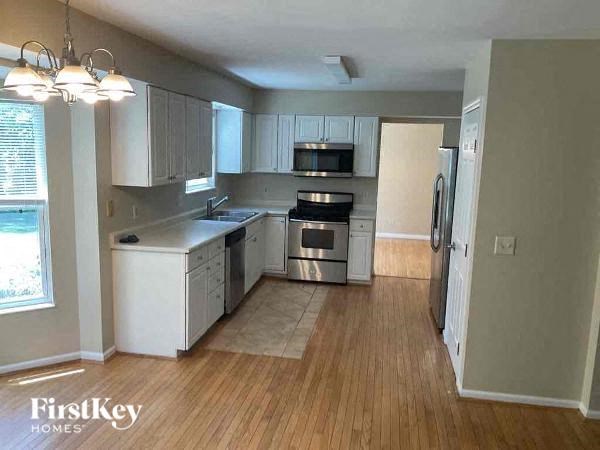 A kitchen with wooden floors and white appliances.