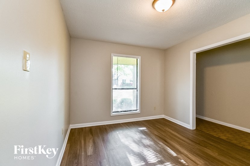 an empty living room with a window and wooden floors