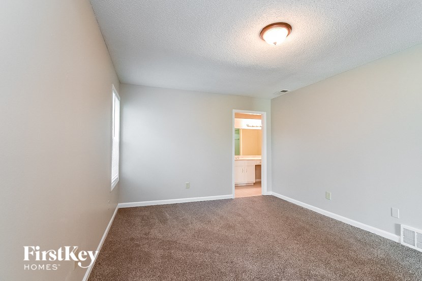 an empty living room with a carpeted floor and a bathroom