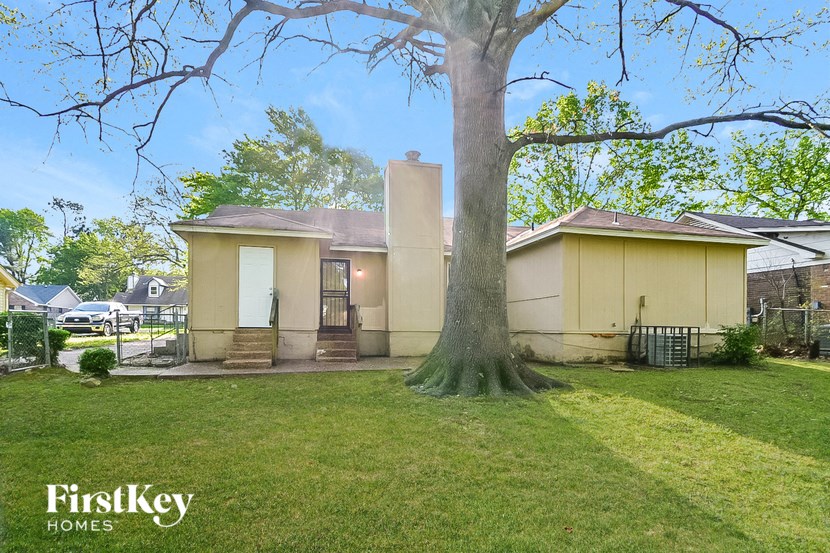 a small yellow house with a tree in the yard