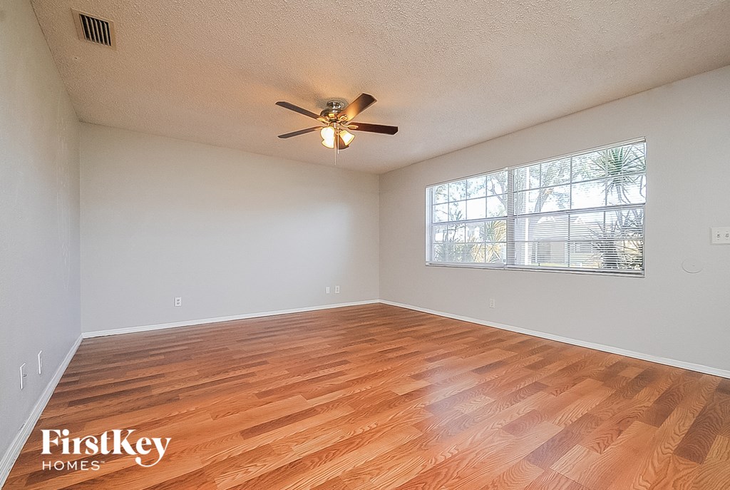 A room with wooden flooring and a ceiling fan.