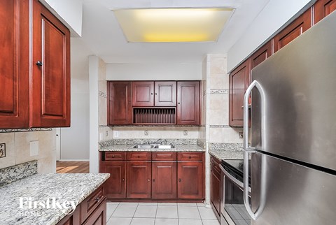 A kitchen with wooden cabinets and a stainless steel refrigerator.