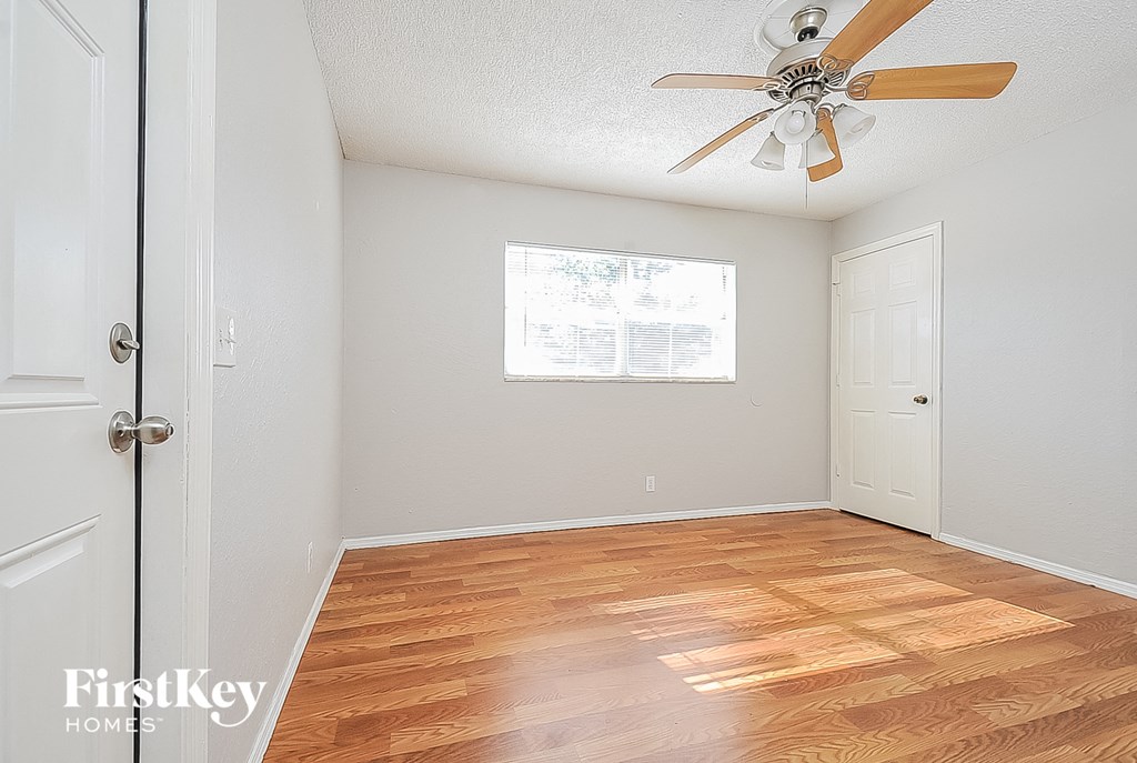 A room with a ceiling fan and wooden flooring.
