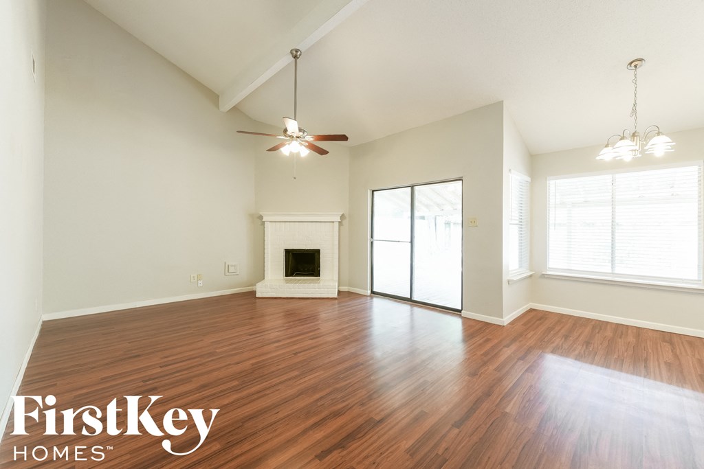 A spacious room with wood flooring and a fireplace.