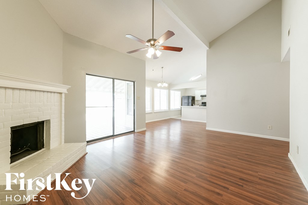 A spacious living room with a fireplace and wood flooring.