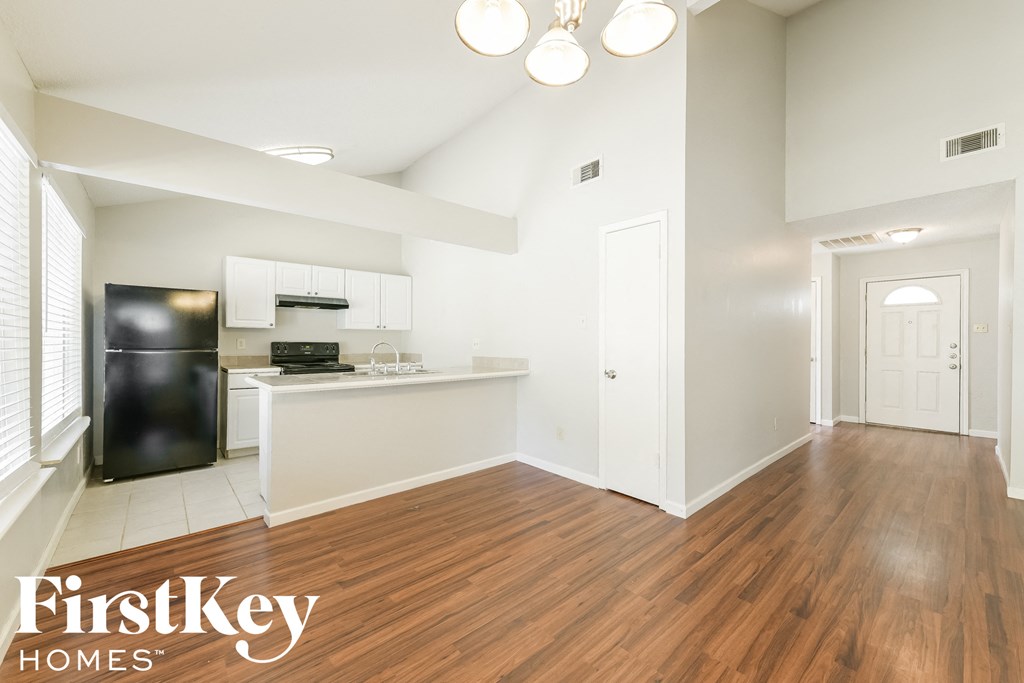 A clean, empty room with wood flooring and white walls.