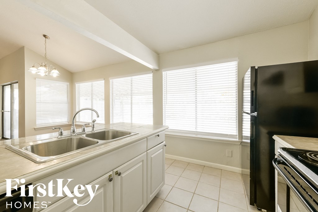 A kitchen with a stainless steel refrigerator and a sink with a faucet.