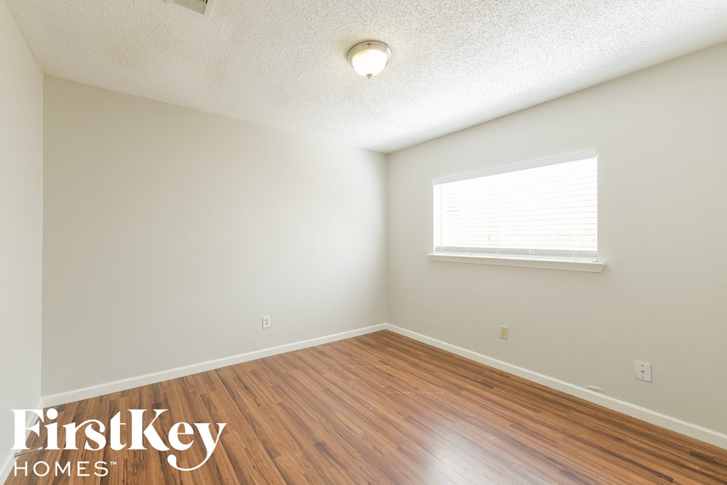A room with wooden floors and a window with blinds.