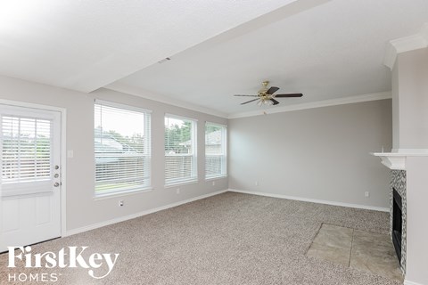 an empty living room with a ceiling fan and windows