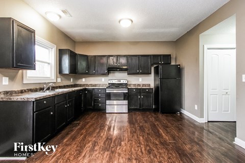 A kitchen with black cabinets and a wooden floor.