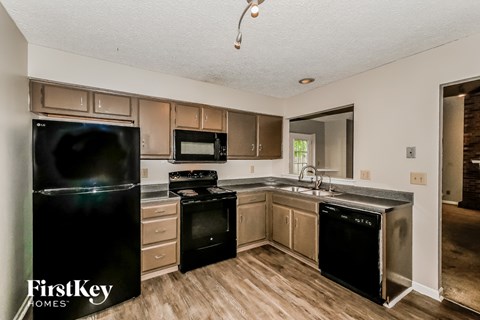 A kitchen with a black fridge and black appliances.
