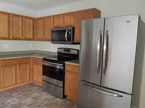 A kitchen with a stainless steel refrigerator and a black microwave above the stove.
