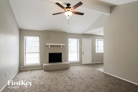 A spacious living room with a fireplace and a ceiling fan.