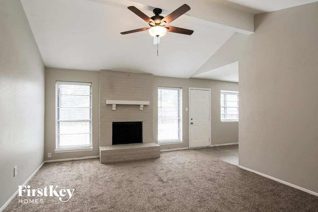 A spacious living room with a fireplace and a ceiling fan.