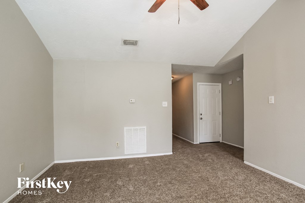 A room with a carpeted floor and a ceiling fan.