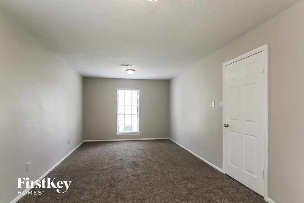 A room with a carpeted floor, a door, and a window.