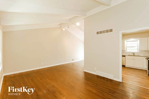 the living room and dining room with wood floors and white walls