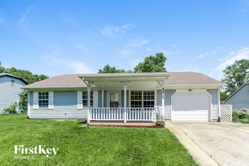 a blue house with a white porch and a white garage door