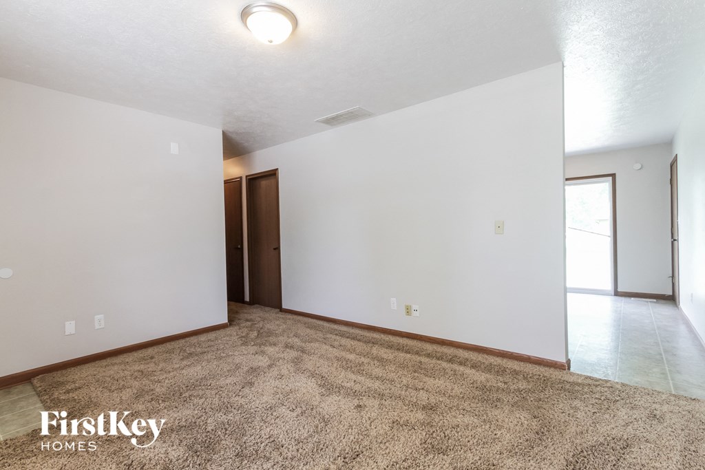 an empty living room with white walls and a beige carpet