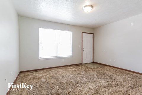 the living room of an apartment with carpet and a door