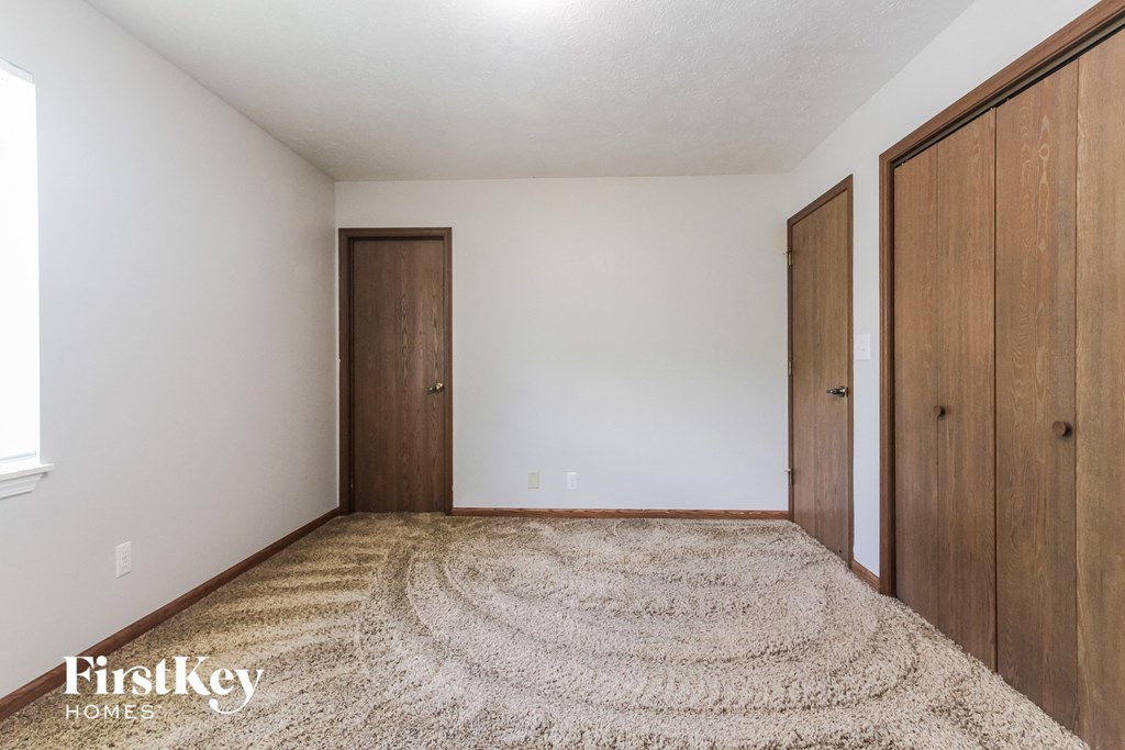a bedroom with three doors and a carpeted floor