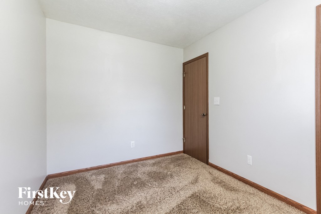 a bedroom with white walls and a wooden door