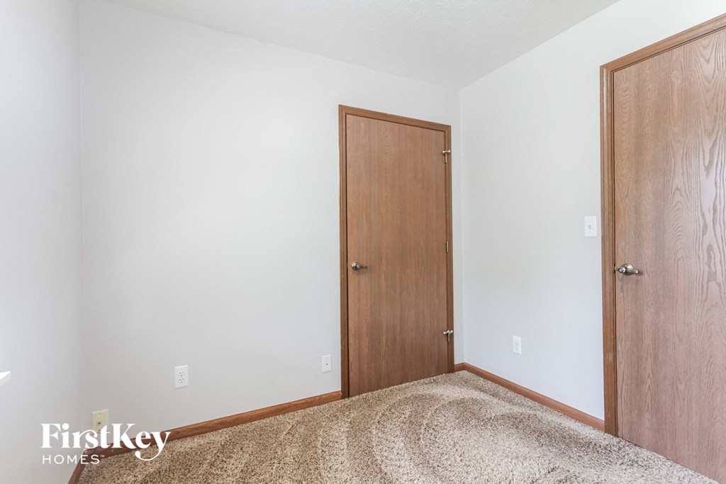 a bedroom with a wooden door and white walls