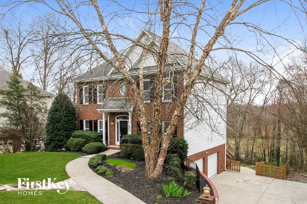 a brick home with a large tree in the front yard