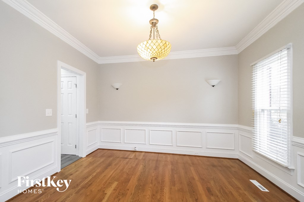 a dining room with white wainscoting and a chandelier