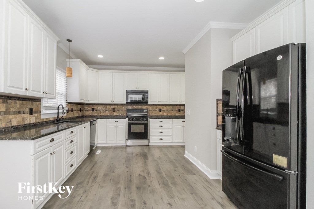 a renovated kitchen with white cabinets and black appliances