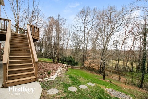 stairs to the deck of a cabin with trees and a river