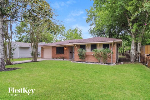 a small brick house with a lawn and trees