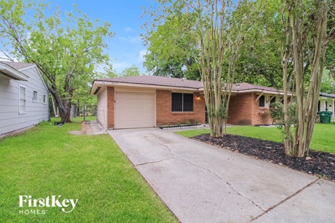 a small brick house with a driveway in front of it