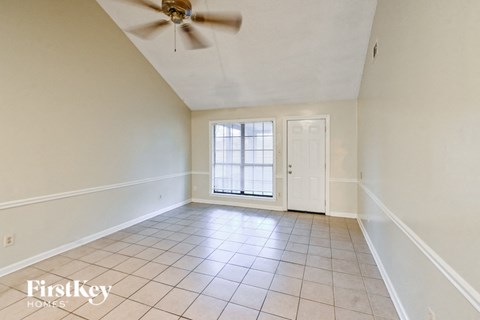 an empty living room with white walls and a ceiling fan