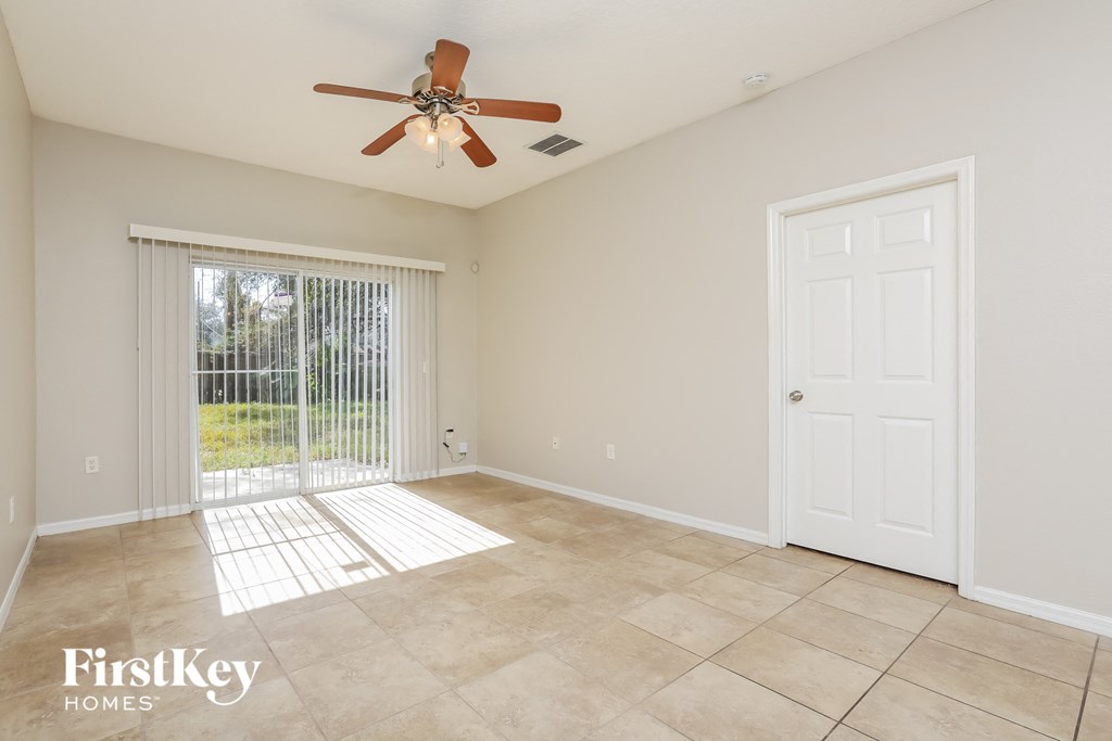 a living room with a ceiling fan and a door to a patio