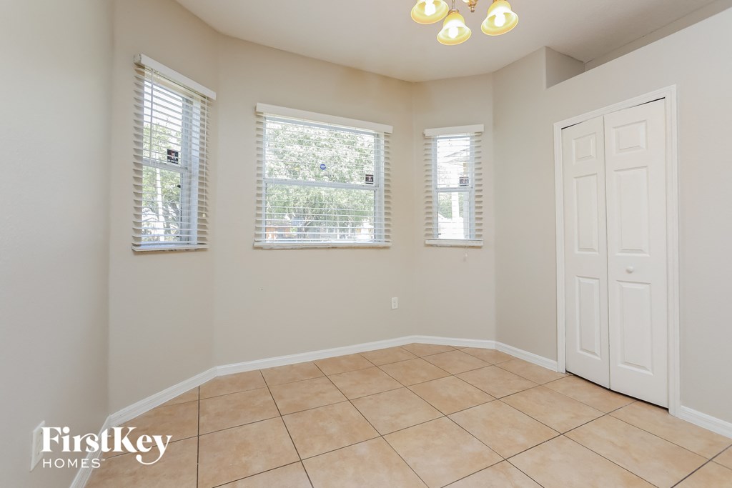 an empty dining room with three windows and a white door
