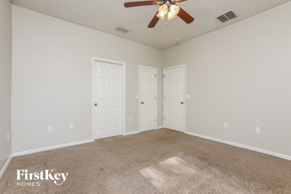 a bedroom with two doors and a ceiling fan
