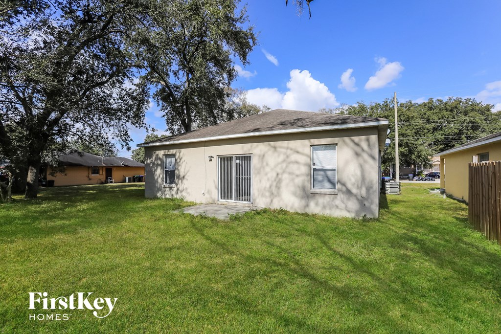 a small white house in a grassy yard with a tree