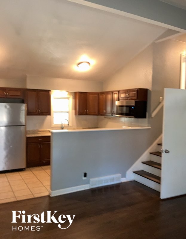 A kitchen with wooden cabinets and a stainless steel refrigerator.